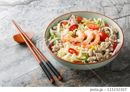 Thai Yum Mama salad with instant noodles, shrimp, minced pork, tomatoes, herbs, celery and onions close-up in a bowl. Horizontal Thai Yum Mama salad with instant noodles, shrimp, minced pork, tomatoes, herbs, celery and onions close-up in a bowl. Horizontal 115232307