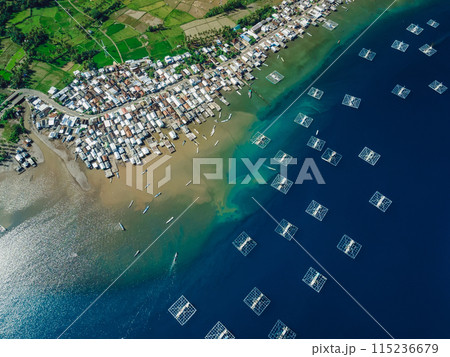 Fishing town and fishing boats in blue ocean on Sumbawa island. Scenic aerial view. Fishing town and fishing boats in blue ocean on Sumbawa island. Scenic aerial view. 115236679