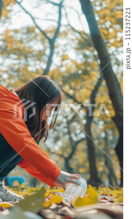 A girl removes plastic bottles and garbage in the forest, taking care of the cleanliness of the forest A girl removes plastic bottles and garbage in the forest, taking care of the cleanliness of the forest 115237223