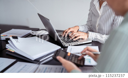 Two business real estate seller using calculator to calculating and discussion about property investment while typing terms data about home sales contract and home insurance on laptop in office Two business real estate seller using calculator to calculating and discussion about property investment while typing terms data about home sales contract and home insurance on laptop in office 115237237