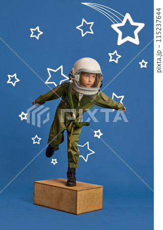 Child's imagination. Little explorer, boy flight in astronaut costume with stars around against blue studio background. 115237644