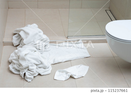 Pile of dirty used towels on the hotel bathroom floor. Housekeeping replace only the used towels on floor with clean ones. Saving water, soap, energy as a green policy. 115237661