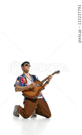 Poster. Stylish young man, bass guitarist kneels dramatically while playing electric guitar against white studio background. Poster. Stylish young man, bass guitarist kneels dramatically while playing electric guitar against white studio background. 115237791