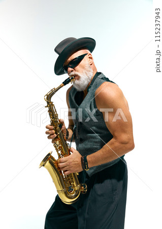 Artistic mature man with beard dressed vintage fashion outfit plays golden saxophone against white studio background. Artistic mature man with beard dressed vintage fashion outfit plays golden saxophone against white studio background. 115237943