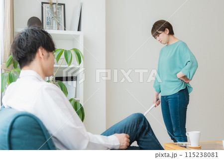 掃除をする女性とスマホをいじる男性 115238081