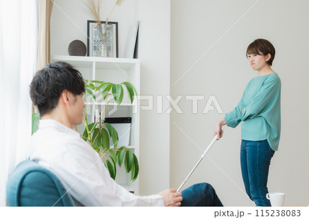 掃除をする女性とスマホをいじる男性 掃除をする女性とスマホをいじる男性 115238083