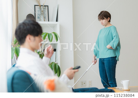 掃除をする女性とスマホをいじる男性 115238084