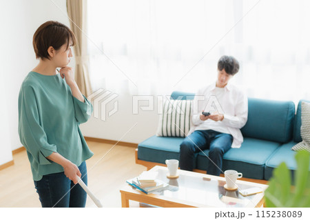 掃除をする女性とスマホをいじる男性 掃除をする女性とスマホをいじる男性 115238089