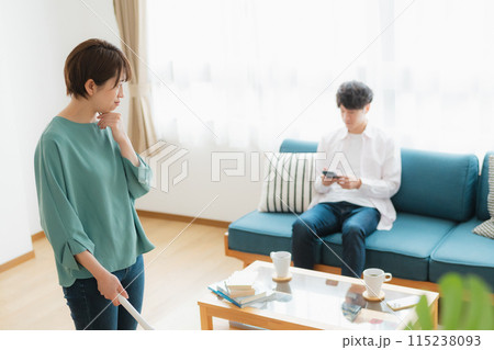 掃除をする女性とスマホをいじる男性 115238093