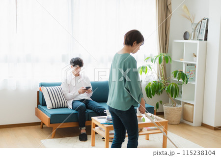 掃除をする女性とスマホをいじる男性 115238104