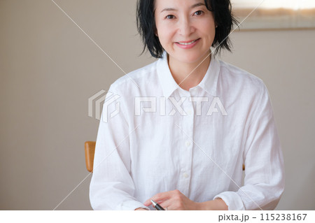 リビングで家族へ手紙を書いているミドル女性 リビングで家族へ手紙を書いているミドル女性 115238167