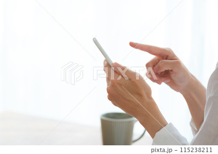 リビングでスマホで情報検索してメモを取るミドル女性 115238211