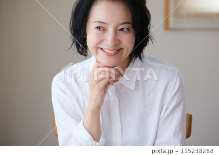 リビングで家族へ手紙を書いているミドル女性 リビングで家族へ手紙を書いているミドル女性 115238288