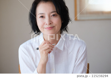 リビングで家族へ手紙を書いているミドル女性 リビングで家族へ手紙を書いているミドル女性 115238294