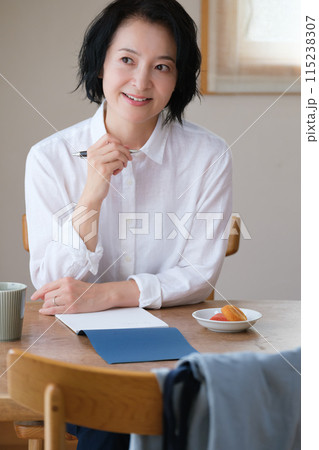 リビングで家族へ手紙を書いているミドル女性 115238307