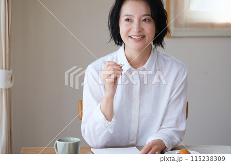 リビングで家族へ手紙を書いているミドル女性 115238309