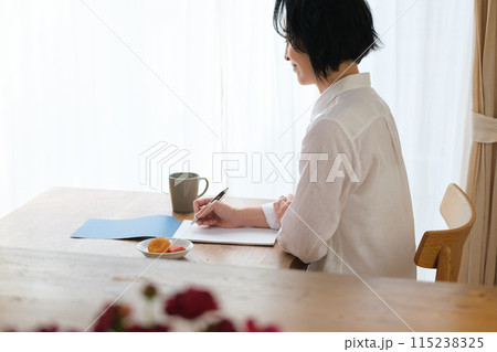 リビングで家族へ手紙を書いているミドル女性 115238325