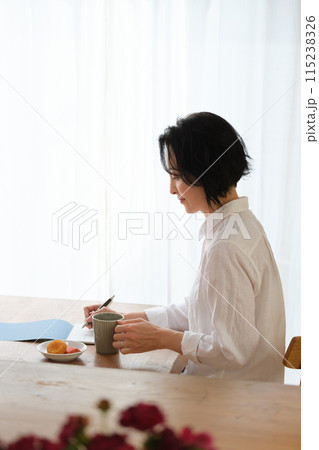 リビングで家族へ手紙を書いているミドル女性 115238326