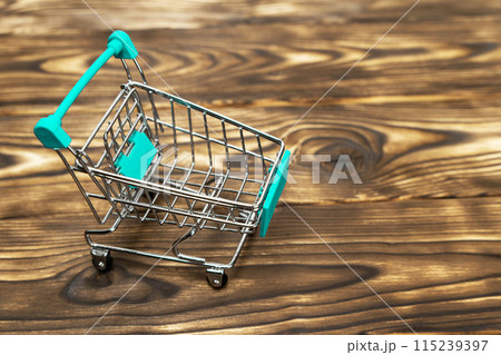miniature shopping cart on a wooden background. The concept of consumption, holiday purchases 115239397