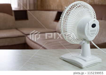 White plastic fan back view with the mode turned on for cool air in room, increasing the temperature of house on hot day using an electronic fan 115239955