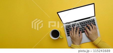Woman hands typing on laptop keyboard over yellow background with copy space 115241689