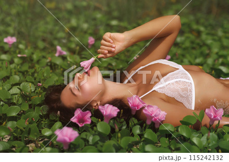 Sensual Woman in White Lingerie Enjoying Flowers in a Lush Green Field Sensual Woman in White Lingerie Enjoying Flowers in a Lush Green Field 115242132