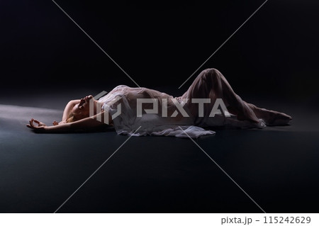 Unrecognizable naked woman silhouette laying in white fabric 115242629