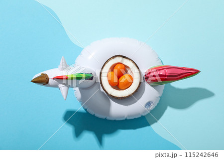 Inflatable ring for swimming and kumquat in half coconut on blue background, top view 115242646