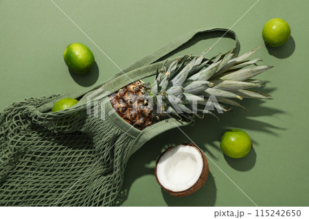 Tropical fruit in bag on green background, top view Tropical fruit in bag on green background, top view 115242650