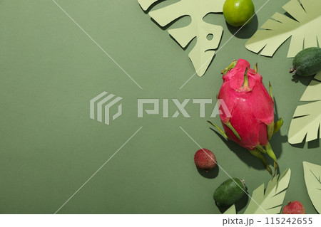 Tropical fruit and paper tropical leaves on green background, space for text 115242655