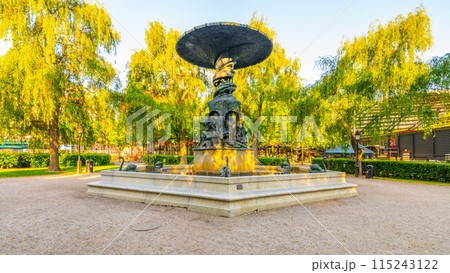 Molins Fountain stands as a centerpiece in Kings Garden, Stockholm, basked in golden sunset light, flanked by lush weeping willows. Sweden 115243122