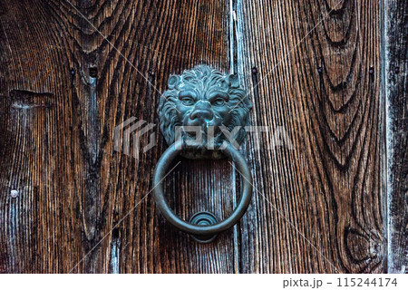 Old-fashioned door knocker in shape of a lion head somewhere on a door in downtown Matera 115244174