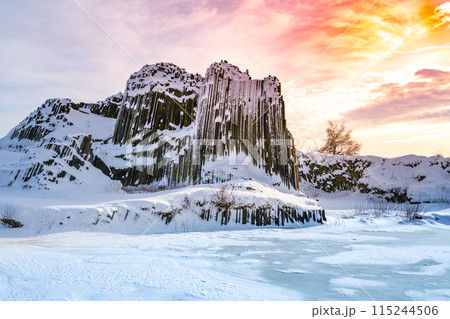 Panska skala - rock formation of pentagonal and hexagonal basalt columns. Looks like giant organ pipes. Covered by snow and ice in winter time. Kamenicky Senov, Czech Republic. 115244506