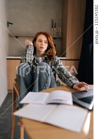 Vertical portrait of serious female working from home office using laptop, staring at device screen looking pensive and thoughtful, search solution, prepare report or research, doing freelance job. 115245382