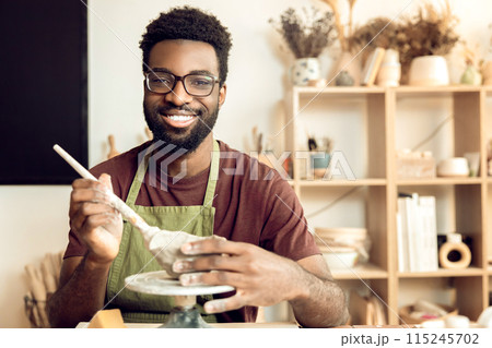 Smiling man painting pottery and looking enjoyed 115245702