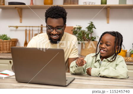 African American father helps his daughter with lessons during distance education 115245740