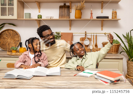 Black man making selfie with daughters while helping kids with homework 115245756