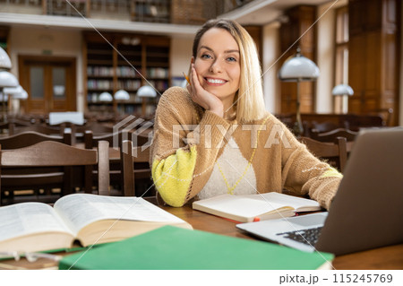 Blonde smiling woman at the laptop in the library 115245769
