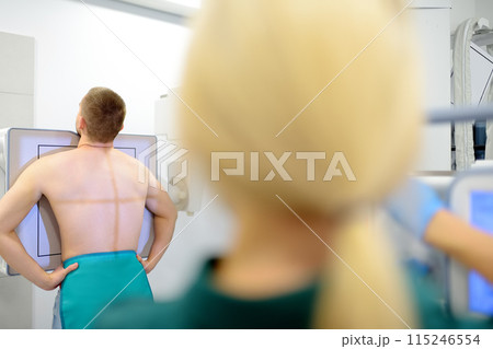 Female radiologist is going to take an Xray of patient in X-ray room of modern clinic. Doctor prepares patient for fluorography. Medical examination of people is prevention of tuberculosis spread Female radiologist is going to take an Xray of patient in X-ray room of modern clinic. Doctor prepares patient for fluorography. Medical examination of people is prevention of tuberculosis spread 115246554