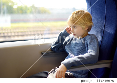Cute preteen boy is traveling in a local train carriage or by railroad while it rain outside. 115246670