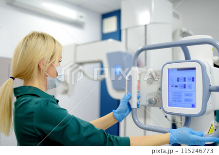 Female technician adjusts X-Ray machine. Female radiologist is going to take an Xray of patient in X-ray room of modern clinic. 115246773