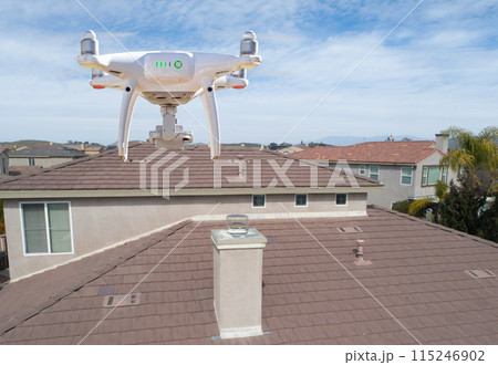 Quadcopter UAV Drone Flying A Residential Roof Inspection. 115246902