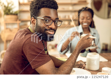 Two people sitting at the table and working with ceramic products Two people sitting at the table and working with ceramic products 115247120