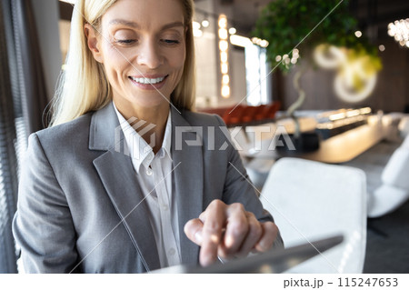 Businesswoman using digital tablet while standing near window in office Businesswoman using digital tablet while standing near window in office 115247653