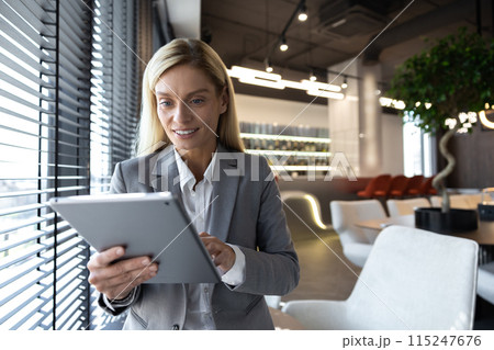 Professional businesswoman working on tablet checking emails while standing 115247676