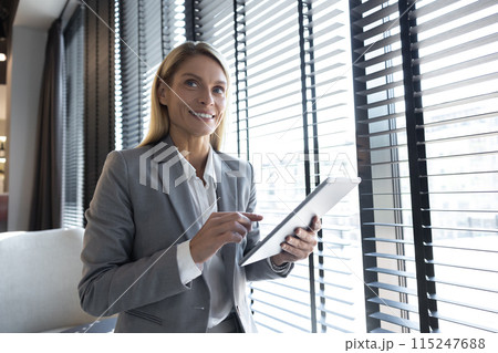 Confident business leader using tablet in office interior 115247688