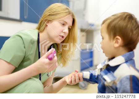 A cute toddler boy is at an appointment with a caring pediatrician. The doctor ENT is examines nose of a little patient using flashligh. A cute toddler boy is at an appointment with a caring pediatrician. The doctor ENT is examines nose of a little patient using flashligh. 115247778