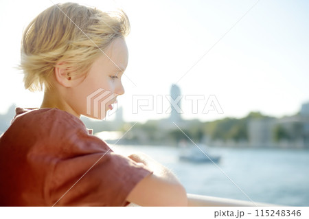Cute blonde preteen boy is traveling by boat or ferry on the sea. Family vacations on ocean or sea. Summer leisure for families with kids. Cute blonde preteen boy is traveling by boat or ferry on the sea. Family vacations on ocean or sea. Summer leisure for families with kids. 115248346