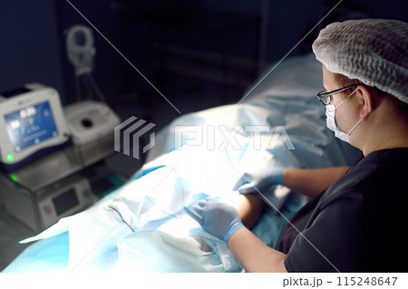 Professional vascular surgeon is in the operating room of the clinic during vein surgery. Phlebectomy. Modern technology of deep vein thrombosis treatment. 115248647