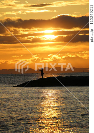 海に沈む夕日と釣りをする人 海に沈む夕日と釣りをする人 115249215